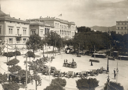 Η πλατεία Συντάγματος την περίοδο των Βαλκανικών Πολέμων. Στο κέντρο εκτίθενται πυροβόλα-λάφυρα του πολέμου. Αριστερά το ξενοδοχείο Μεγ. Βρετανία και τα μέγαρα Σκουλούδη και Βούρου, πριν δώσουν τη θέση τους σε ξενοδοχεία (1912-1913) 